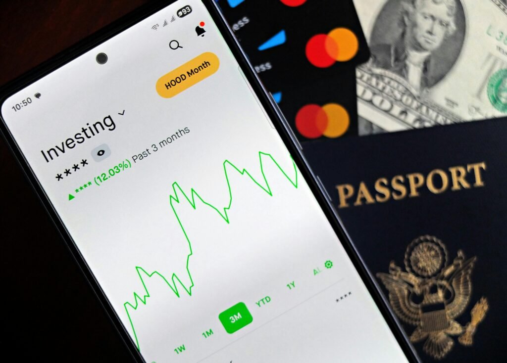 How to Start Stock Investing for Beginners - Full Guide Smartphone showing stock market app with travel essentials: passport, money, and cards.