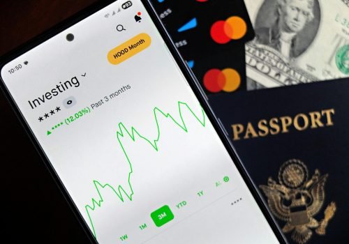 Smartphone showing stock market app with travel essentials: passport, money, and cards.